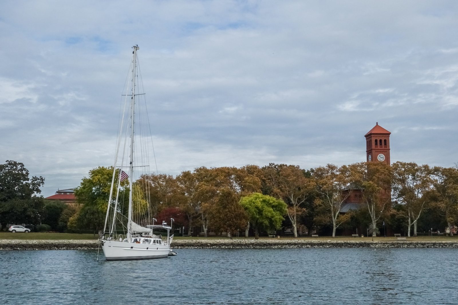 Hampton University's Memorial Church clock tower across the water, with a sailboat moored offshore